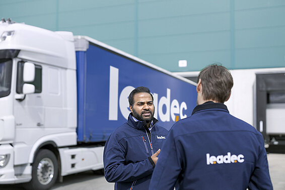 Two male Leadec employees talking in front of a truck.