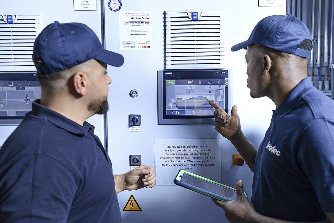 Leadec employees in front of screen of boiler plant.