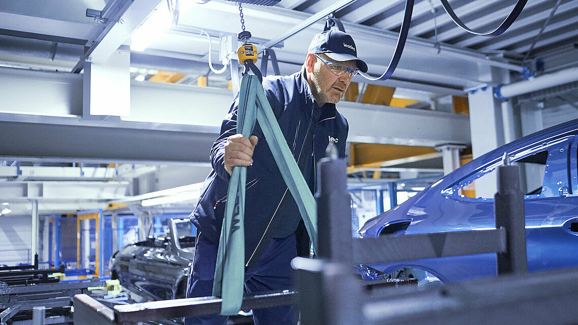 A Leadec employee troubleshooting the conveyor system in an automotive factory.