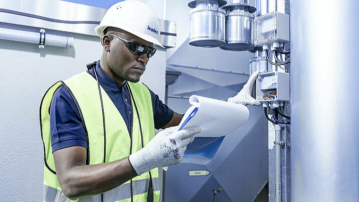 Leadec employee with check list at ventilation system on a factory roof.