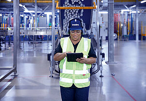 Female Leadec employee with tablet on shopfloor of Food & Beverage factory.