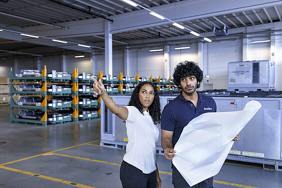 Two Leadec employees discussing while holding a plan of factory layout. 