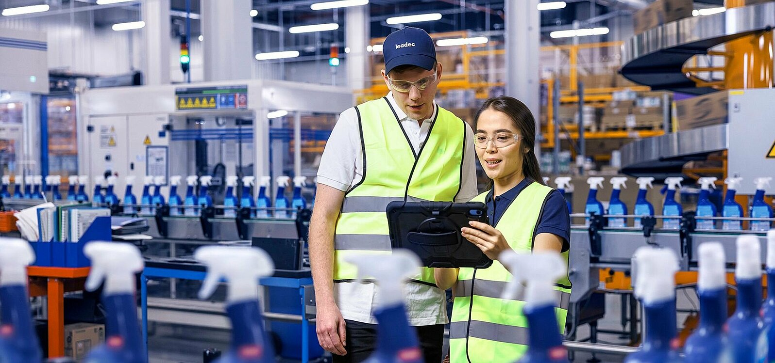 A male and a female Leadec employee looking at a tablet and monitoring the production of cleaning agents.