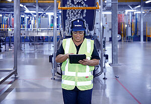 Female Leadec employee with tablet on shopfloor of Food & Beverage factory.