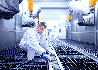 Leadec employee cleaning floor in a paint shop.