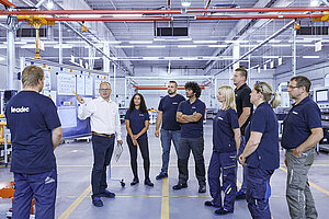 Leadec employees meeting on a shop floor for battery assembly.