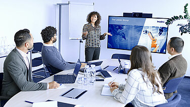 A Leadec employee giving a presentation to several colleagues in a conference room.