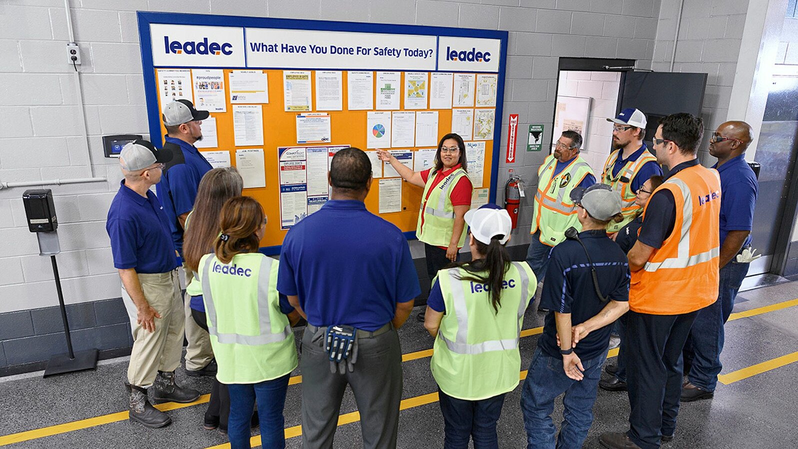 Leadec employees standing in front of a display board discussing tasks.