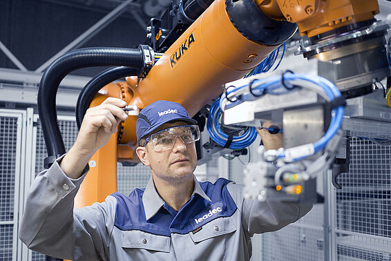 A Leadec employee maintaining a robot in a production.