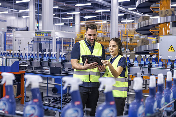 A male and a female Leadec employee looking at a tablet and monitoring the production of cleaning agents.