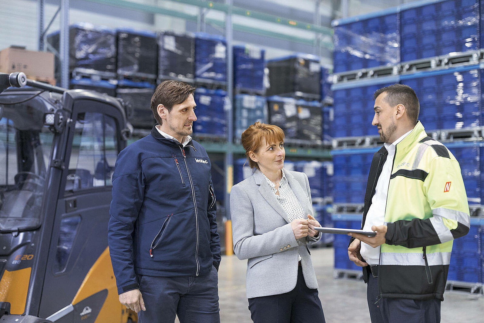 Leadec employees talking with a customer in a warehouse.