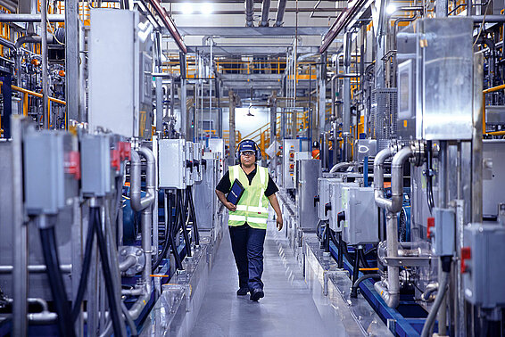 Female Leadec employee with tablet walking on shopfloor of Food & Beverage factory.