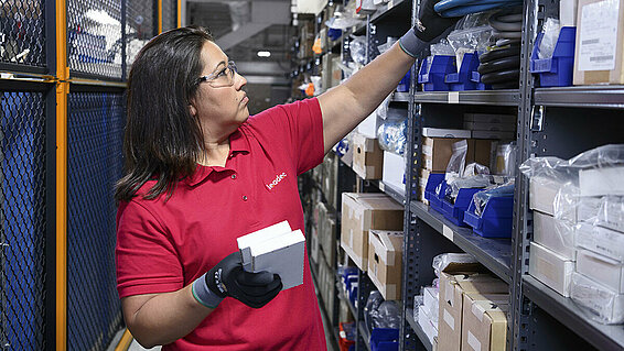 Female Leadec employee restocks inventory of spare parts in a warehouse.