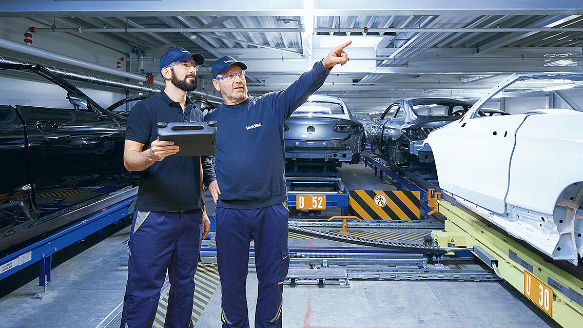 Two Leadec employees monitoring the automated conveyor technology using a tablet.