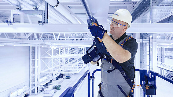 Leadec employee installing media supply on the ceiling of a factory.