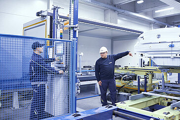 Two Leadec employees troubleshooting the conveyor system in an automotive factory.